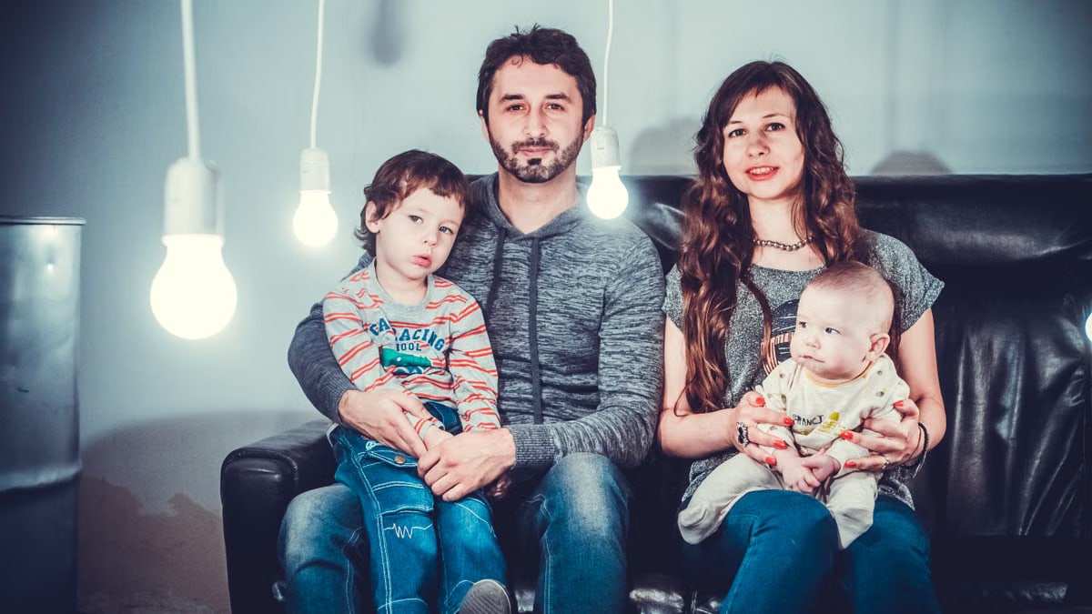 A loving family portrait with parents and children sitting together in a modern, well-lit room.